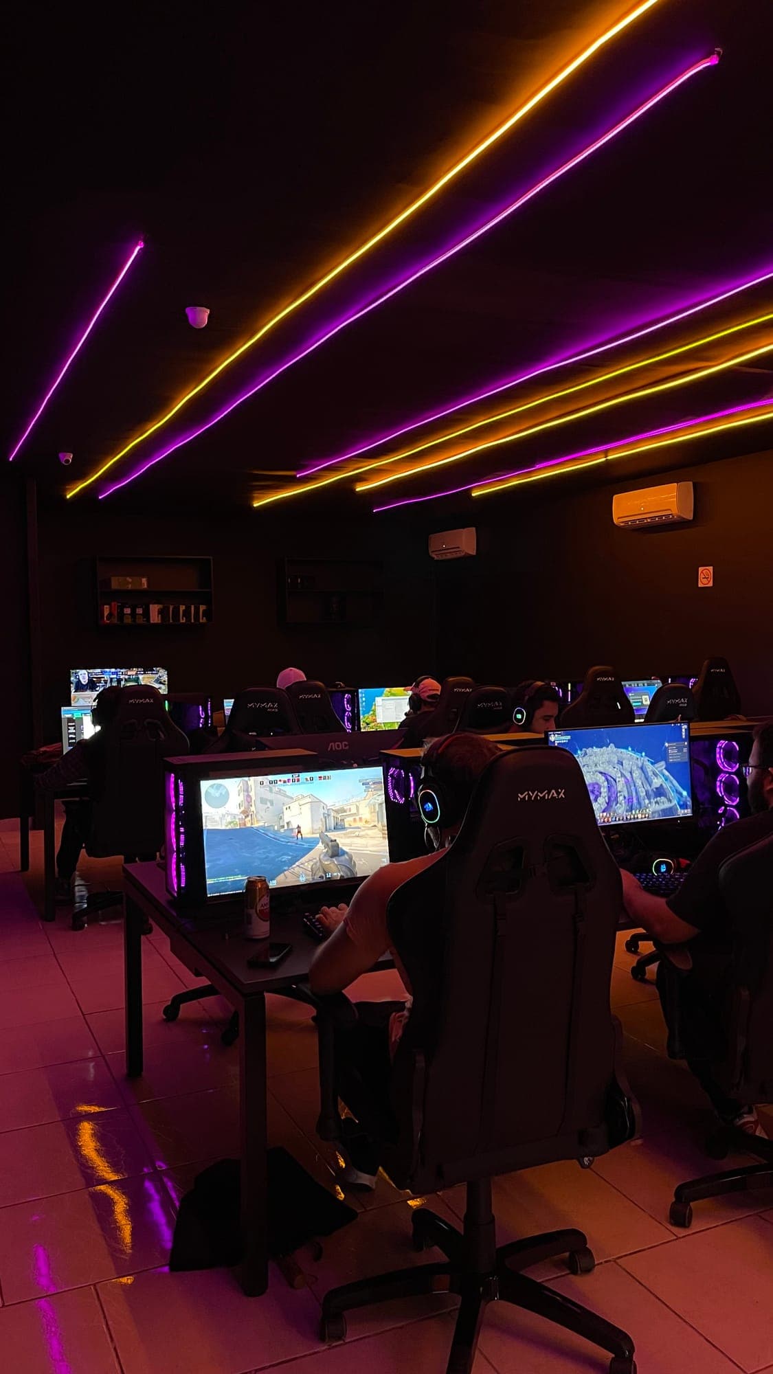 Fileiras de PCs gamer com cadeiras gamer e iluminação neon na GOAT Coração Eucarístico