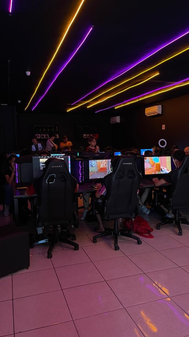 Jogadores em PCs gamer durante evento de Valorant na GOAT, com luzes neon no teto
